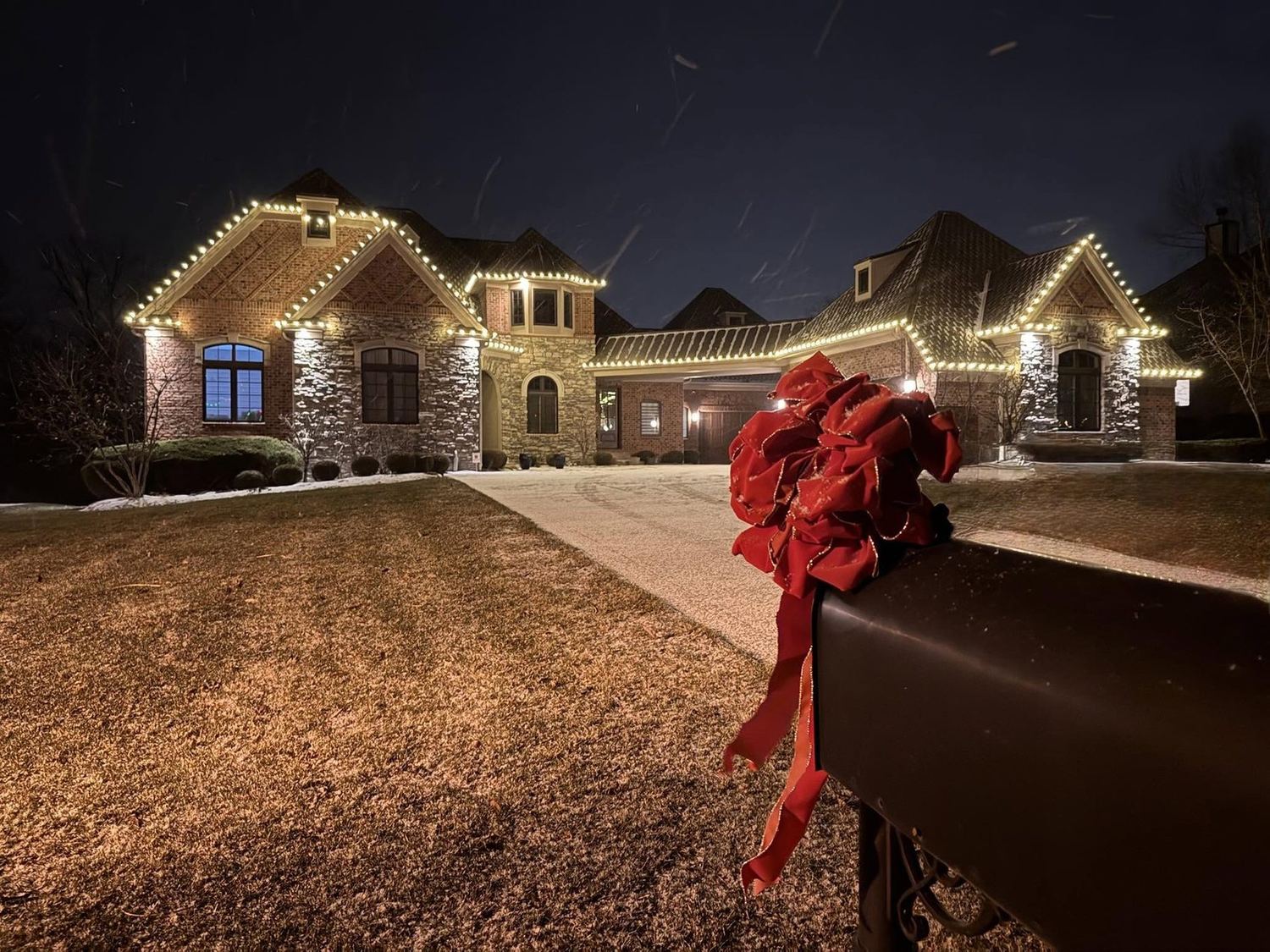 A red bow at the driveway with the house glowing behind it, a Mike&rsquo;s Cincinnati Christmas Lights install